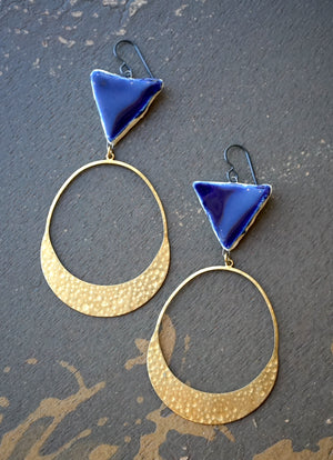 a pair of blue and gold earrings sitting on top of a table