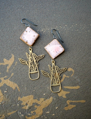 a pair of pink and gold earrings sitting on top of a table