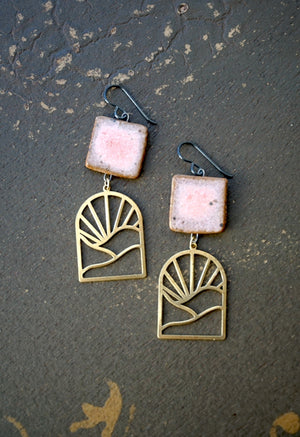 a pair of pink and gold earrings sitting on top of a floor