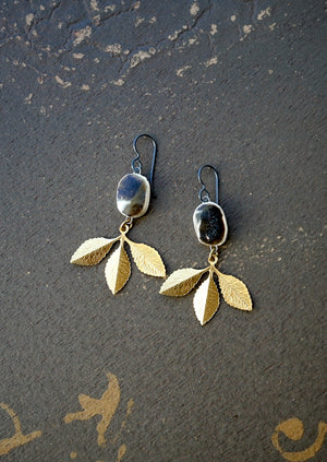 a pair of gold and silver earrings with leaves