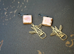 a pair of earrings with flowers and leaves on them