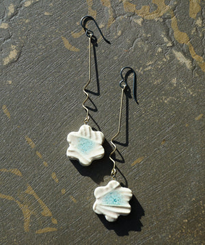 a pair of white flower earrings hanging from a hook