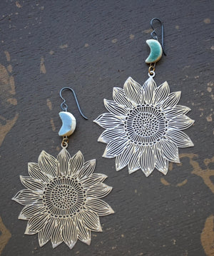 a pair of earrings with a sunflower design